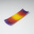 A rectangular ColourWave Glass fused glass plate showcasing a vivid spectrum of colours, with purple at the edges blending into red, orange, and yellow towards the centre. The plate has a smooth surface and its corners gently curve upwards, giving it a contemporary and elegant profile.