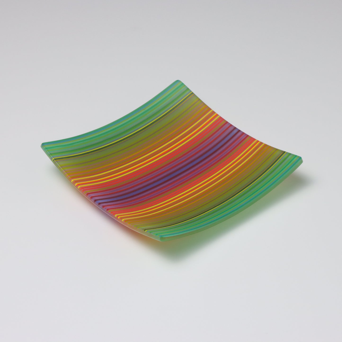 A decorative square shallow glass plate with raised corners and a colourful ColourWave stripe patterns showing key colours of green, yellow, red and blue