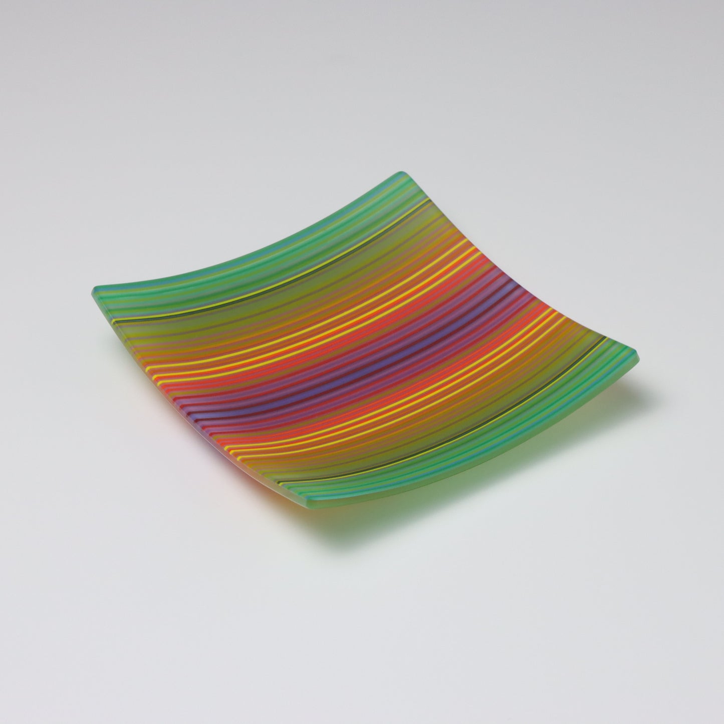 A decorative square shallow glass plate with raised corners and a colourful ColourWave stripe patterns showing key colours of green, yellow, red and blue