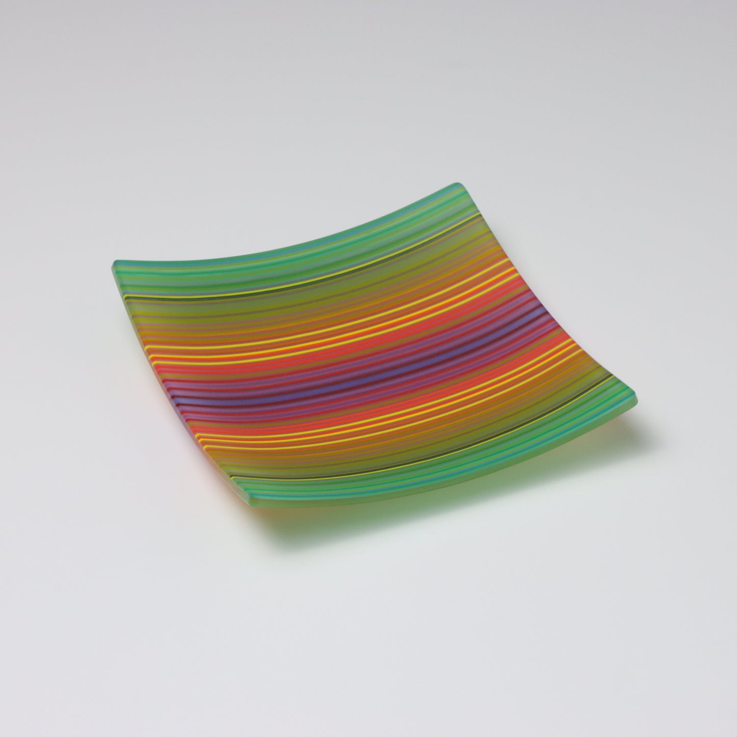 A decorative square shallow glass plate with raised corners and a colourful ColourWave stripe patterns showing key colours of green, yellow, red and blue