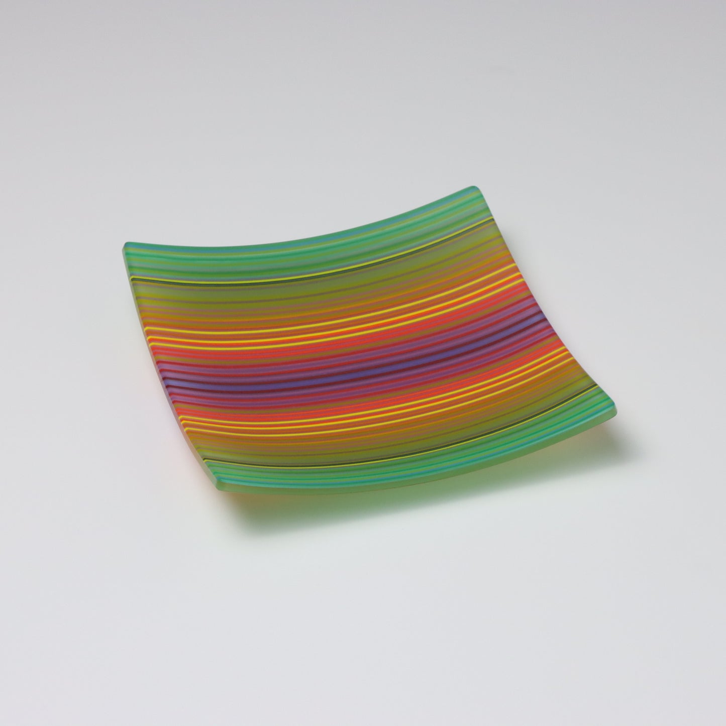 A decorative square shallow glass plate with raised corners and a colourful ColourWave stripe patterns showing key colours of green, yellow, red and blue