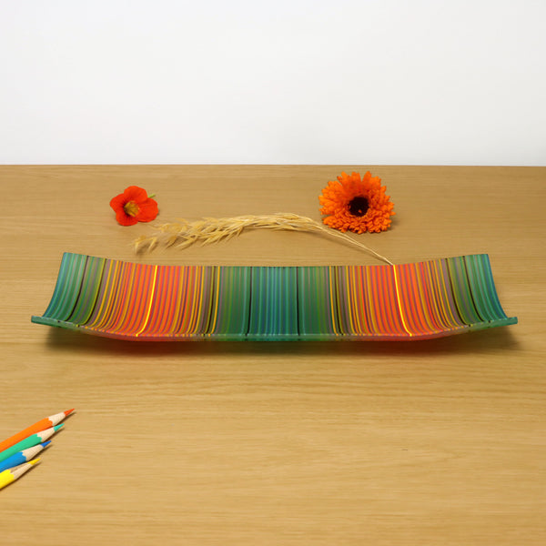 A rectangular ColourWave Glass fused glass plate, featuring vibrant vertical stripes in shades of teal green, orange, and red. The plate is designed with a subtle upward curve at each corner, lending an elegant, raised edge to its form.