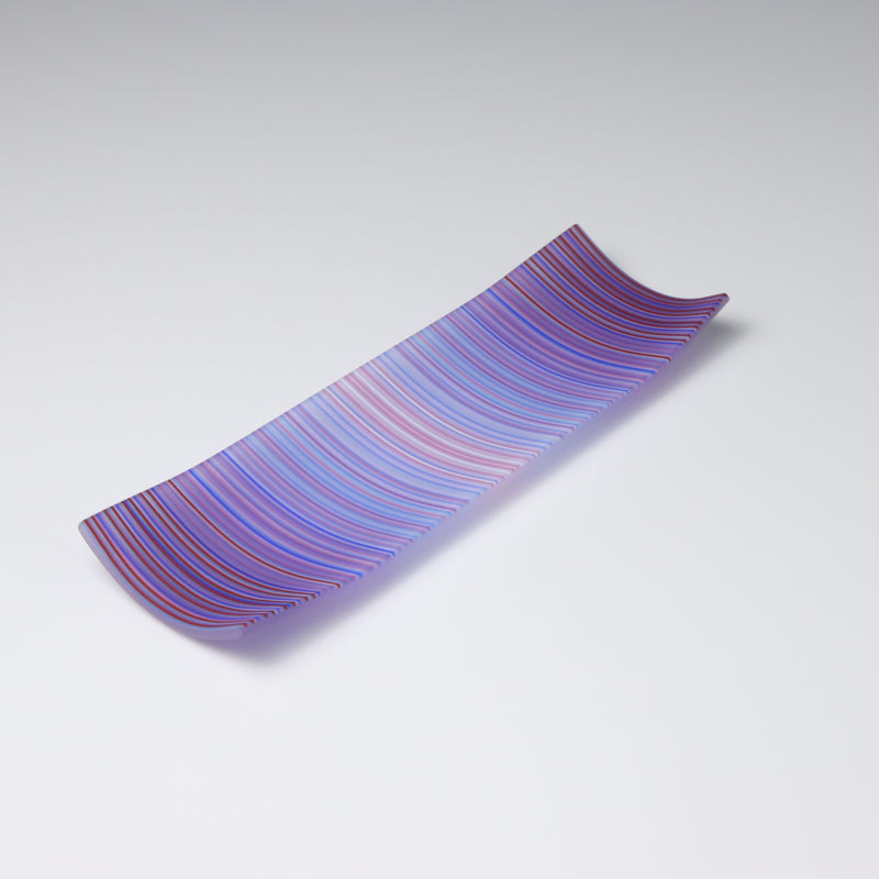A rectangular, floral-inspired patterned fused glass plate with curved-up edges, predominantly in shades of purple, with hints of red and blue.